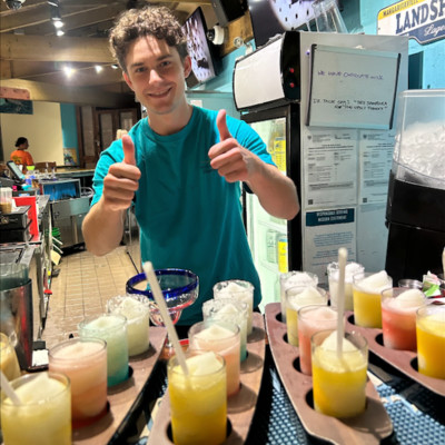 Photo of bartender giving thumbs up behind a variety of frozen margarita sampler flights