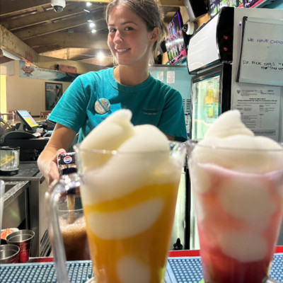 Photo of smiling female bartender preparing frozen tropical drinks