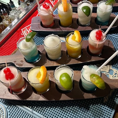 Photo of flight of colorful frozen margarita shots arranged on wooden paddles