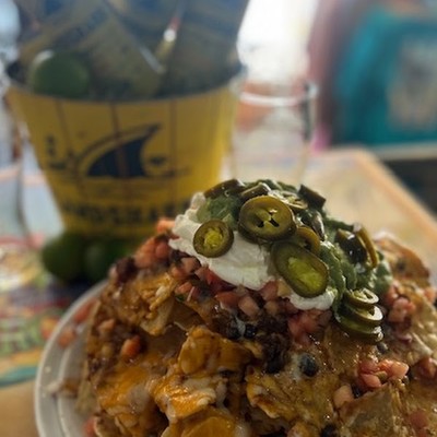 Photo go loaded nachos topped with melted cheese, sliced jalapeños, sour cream, and salsa
