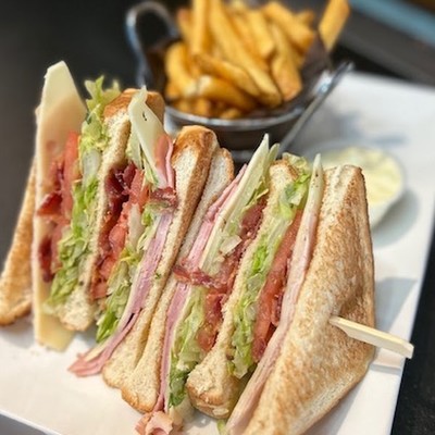Photo os club sandwich cut into quarters, served with side french fries