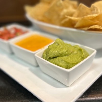 Photo of tortilla chips served with fresh guacamole and dipping sauces