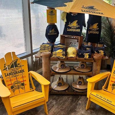 LandShark Lager merchandise display featuring yellow Adirondack chairs, hats, and towels
