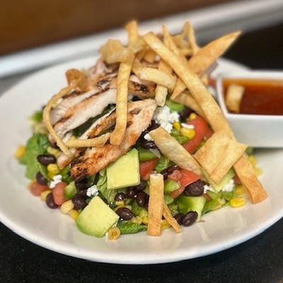 Photo of southwest grilled chicken salad topped with avocado, corn, black beans, and tortilla strips