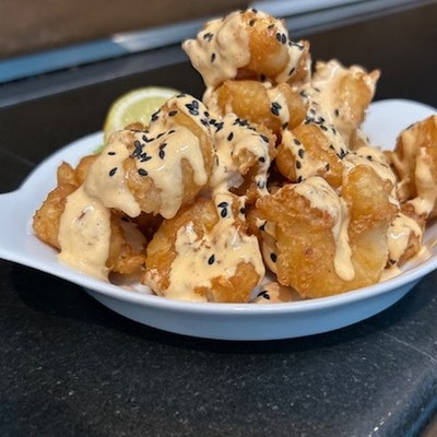 Photo of crispy fried bites drizzled with spicy mayo and topped with sesame seeds