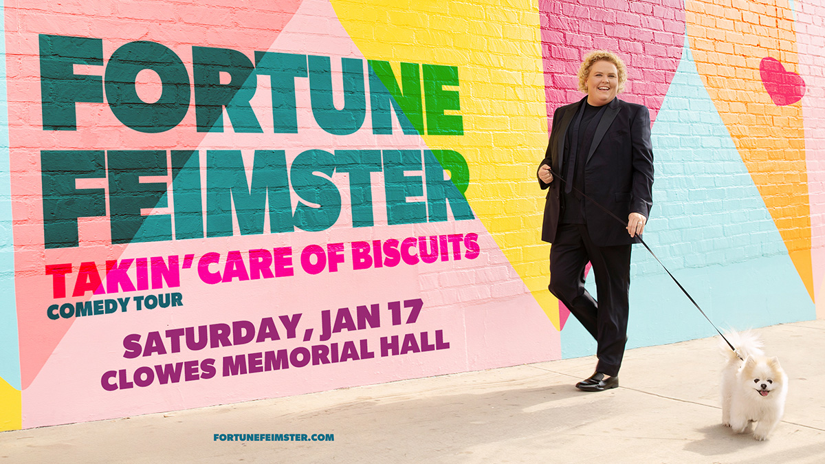 Fortune Feistier walking her dog next to a pastel colored brick wall