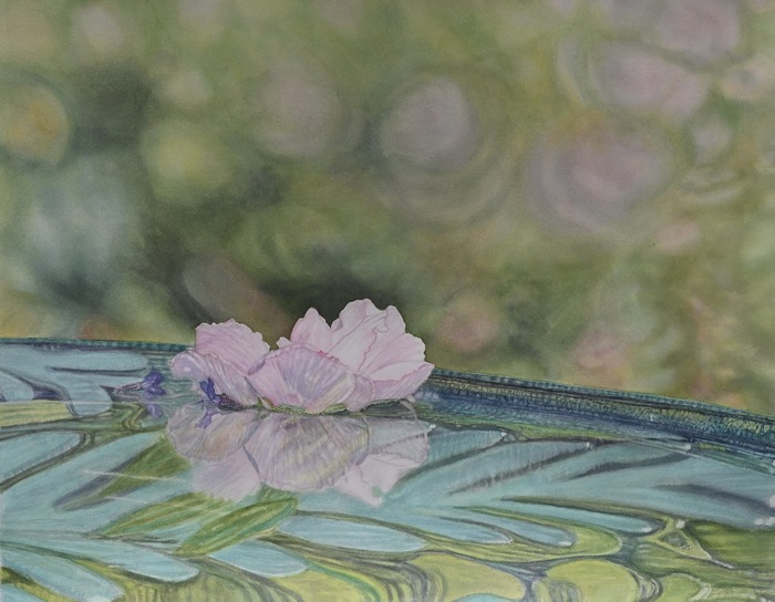 Flowers with reflections floating in a glass birdbath