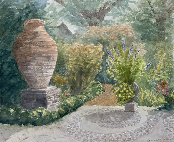 Garden pathway with large urn to the left of circular paved and brick pathway surrounded by a variety of flowers and schrubs.