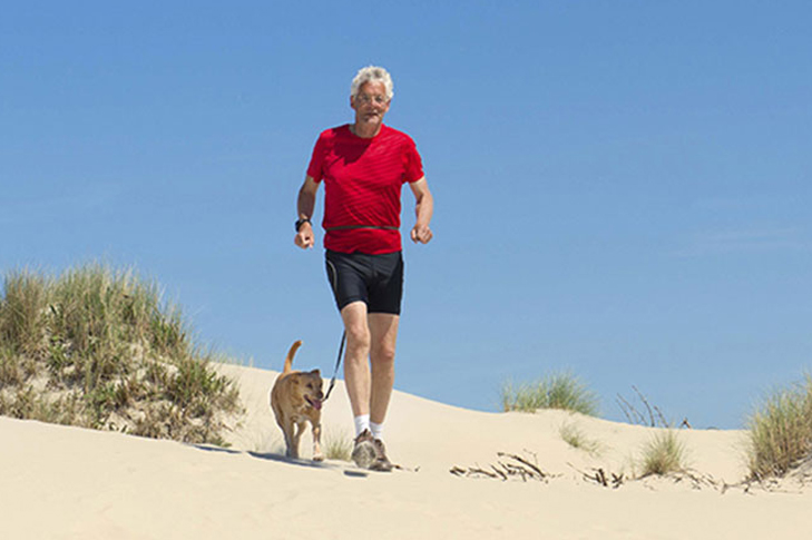 Man running on the beach with his yellow labrador retriever