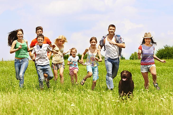 Group of kids running together with a Labrador retriever.