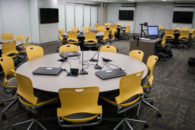 A TILE classroom at the University of Iowa, featuring five tables with three laptops and microphones