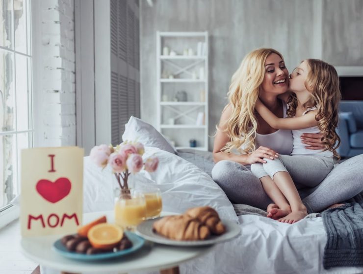 Ideas de regalos para el Día de la Madre 2025 3 Madre e hija abrazadas en la cama durante un desayuno especial por el Día de la Madre.