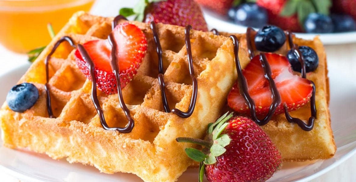 Waffles caseros dorados con fresas y arándanos frescos, decorados con chocolate derretido. Una receta deliciosa y fácil para un desayuno perfecto o brunch irresistible.