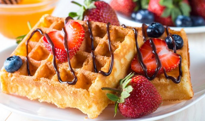 Waffles caseros dorados con fresas y arándanos frescos, decorados con chocolate derretido. Una receta deliciosa y fácil para un desayuno perfecto o brunch irresistible.