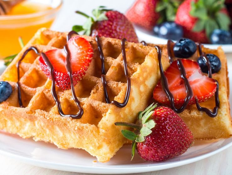 Waffles caseros dorados con fresas y arándanos frescos, decorados con chocolate derretido. Una receta deliciosa y fácil para un desayuno perfecto o brunch irresistible.