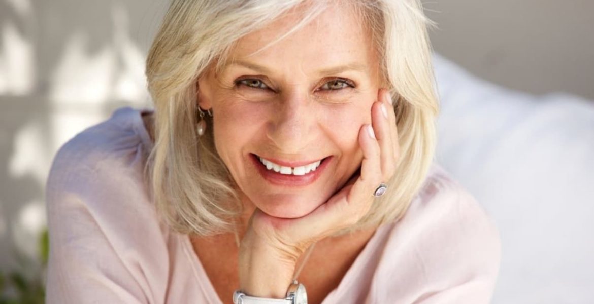 Mujer mayor con cabello con canas, sonriente y elegante