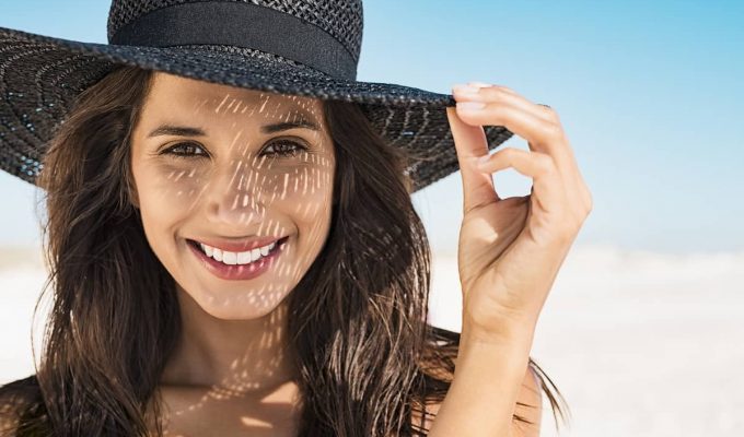 Mujer joven usando un tipo de sombrero negro muy moderno para protegerse del sol