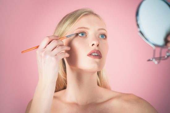 Mujer aplicando sombra de ojos con un pincel de precisión, una de las brochas de ojos esenciales para un look definido y profesional.