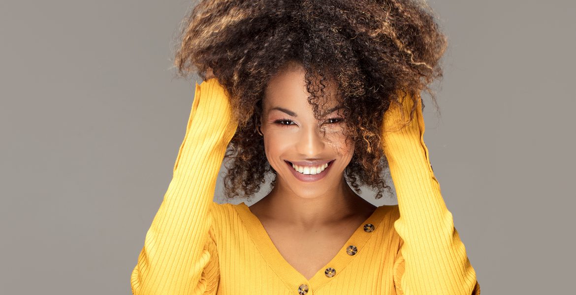Mujer morena de cabello largo con mechas balayage en tonos caramelo para iluminar el rostro