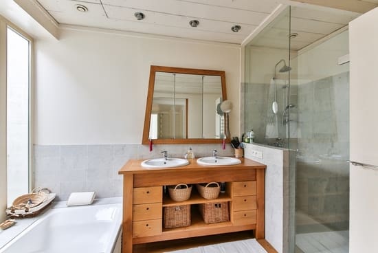 Ideas para baños modernos pequeños y luminosos Baño moderno chico con espejo redondo y mueble de madera clara