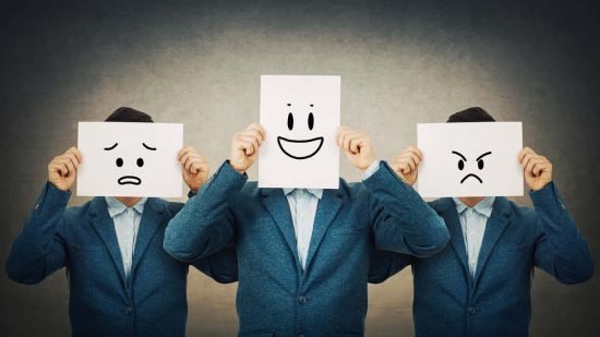 Hacemos lo que somos: llevamos al mundo lo que tenemos dentro. Imagen de 3 hombres con un cartel con caritas con distintas expresiones emocionales