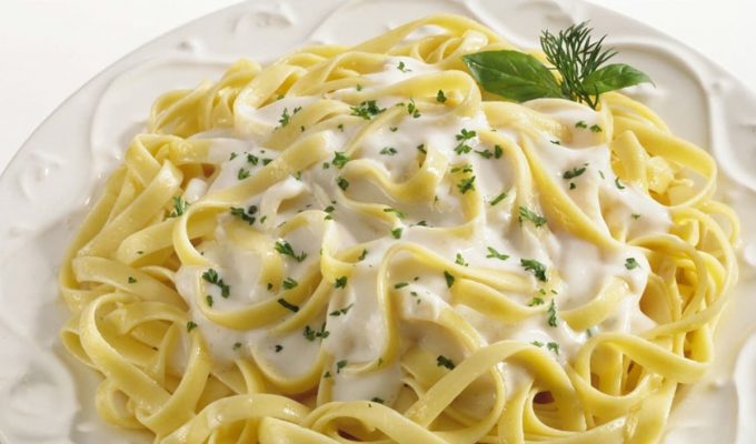 Spaguetti con salsa Alfredo en un plato blanco y decorado