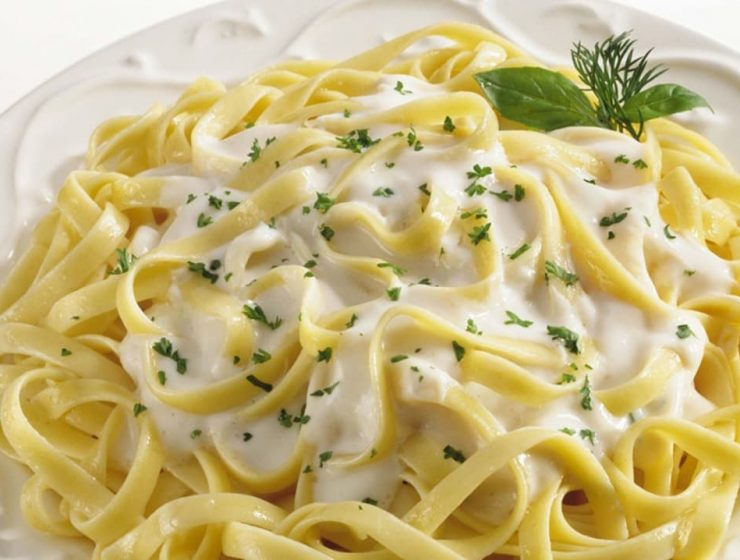 Spaguetti con salsa Alfredo en un plato blanco y decorado