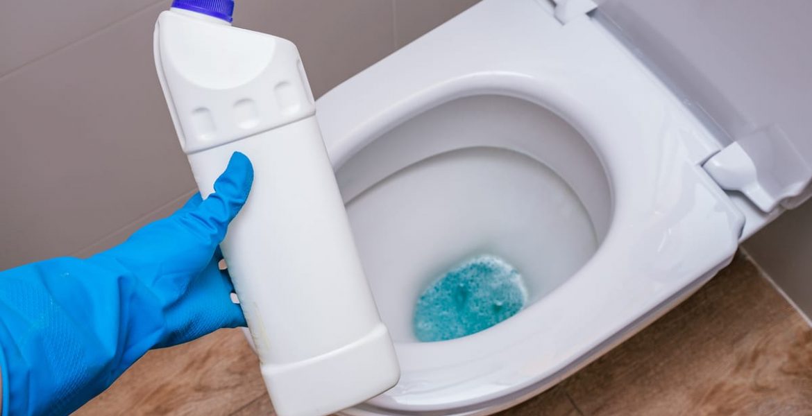 mujer con guante de lavar con un producto para limpiar el inodoro