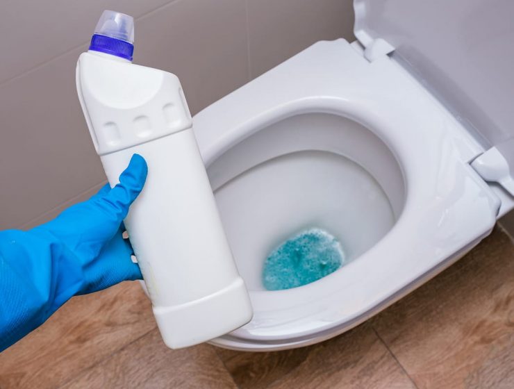 mujer con guante de lavar con un producto para limpiar el inodoro