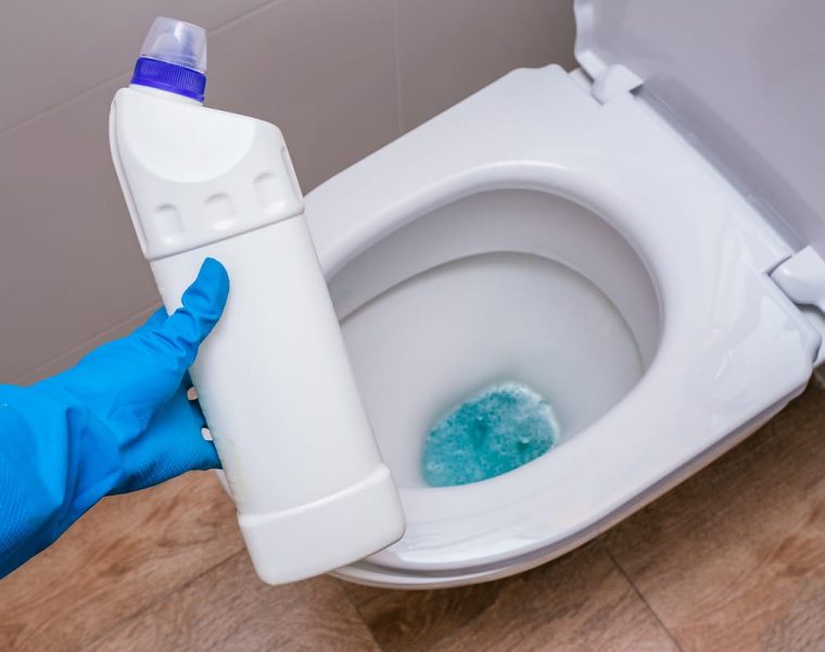 mujer con guante de lavar con un producto para limpiar el inodoro