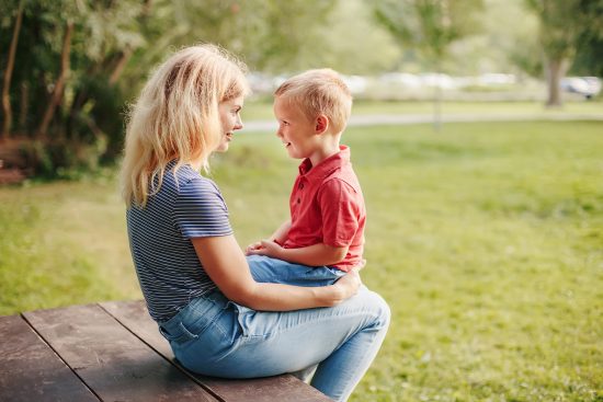 Vínculo madre e hijo: la importancia de la comunicación emocional desde la infancia. Madre e hijo sentados frente a frente en un parque, conversando con ternura.
