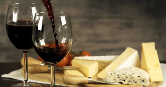 Variedades como Torrontés o Cabernet Franc ganan protagonismo en 2025. Plato de distintos quesos y con dos copas de vino tinto
