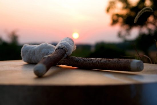 Baquetas de tambor apoyadas al atardecer con el sol en el horizonte.