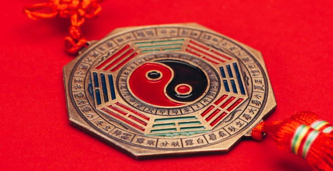 Amuleto tradicional con el símbolo del Yin y Yang sobre fondo rojo, relacionado con la armonía y el equilibrio del horóscopo chino.