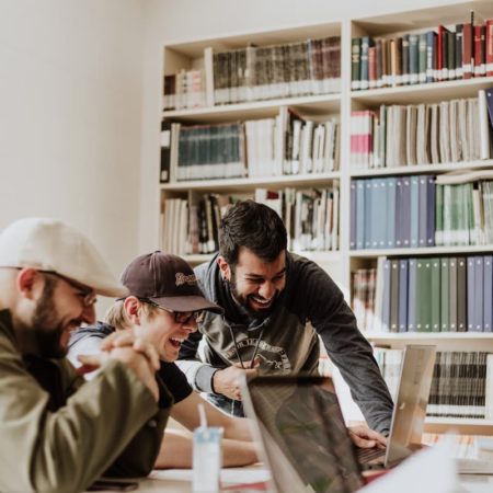 Jóvenes estudiantes trabajando en equipo en una biblioteca, ejemplo de desarrollo de habilidades socioemocionales.