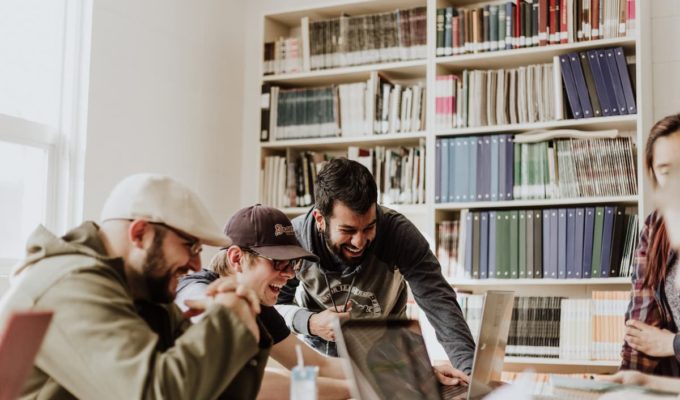 Jóvenes estudiantes trabajando en equipo en una biblioteca, ejemplo de desarrollo de habilidades socioemocionales.