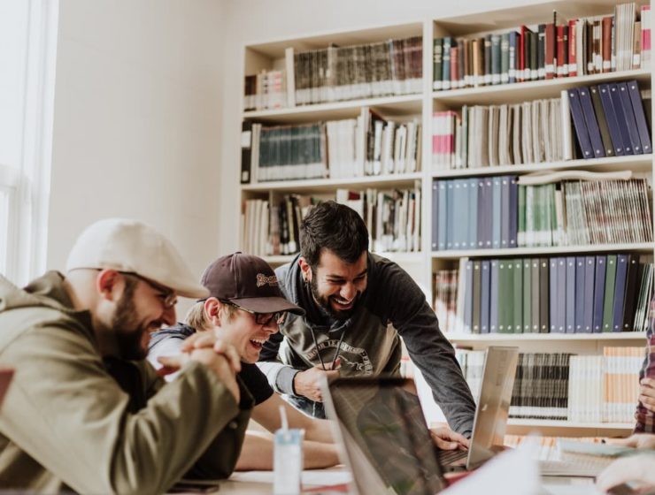 Jóvenes estudiantes trabajando en equipo en una biblioteca, ejemplo de desarrollo de habilidades socioemocionales.