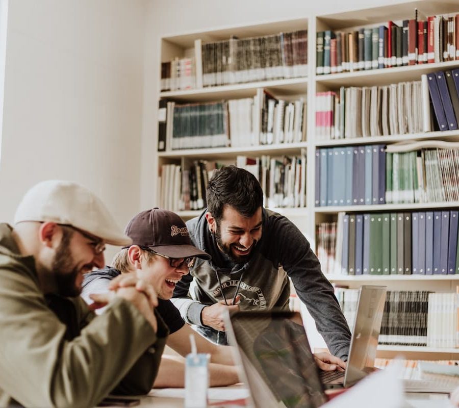 Jóvenes estudiantes trabajando en equipo en una biblioteca, ejemplo de desarrollo de habilidades socioemocionales.