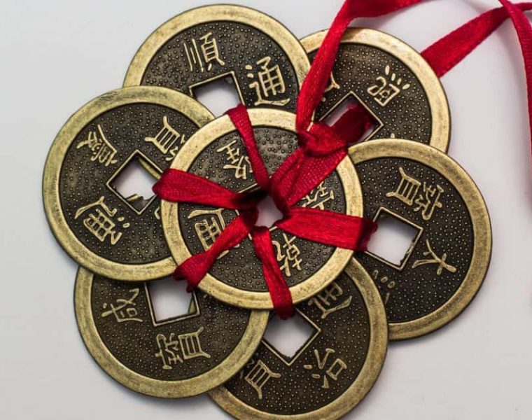 Monedas chinas antiguas atadas con una cinta roja, símbolo tradicional de prosperidad y buena fortuna.