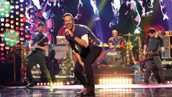 Espectáculo en vivo de Coldplay con luces espectaculares Coldplay en el escenario, Chris Martin en primer plano y la banda tocando con luces de colores