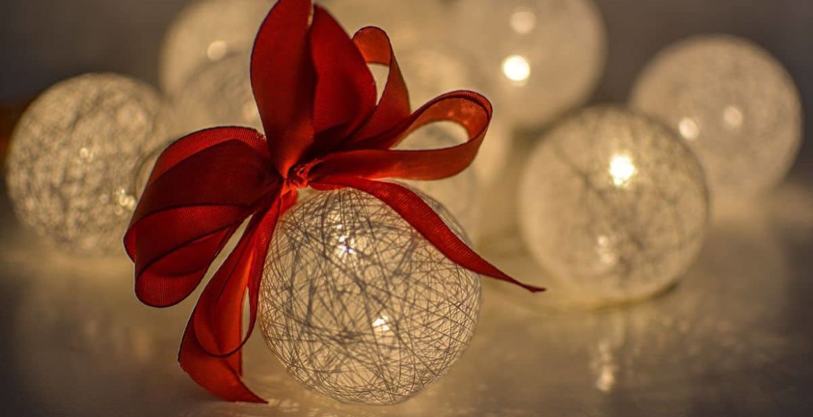 Esferas decorativas navideñas iluminadas con luz cálida y lazo rojo.