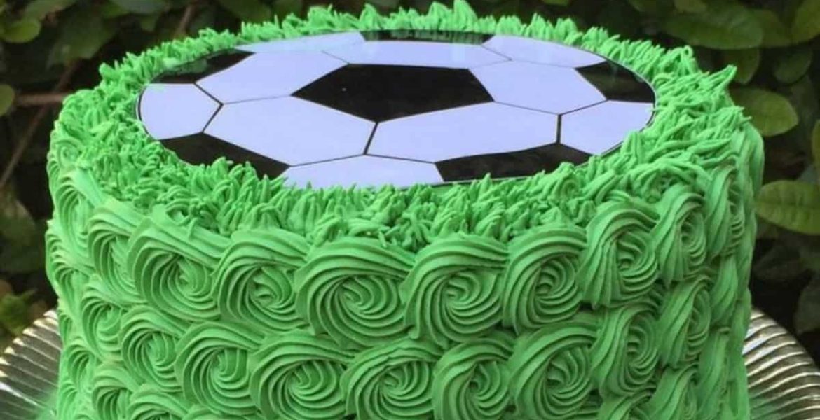 Pastel de futbol soccer con borde de glaseado verde y balón en la parte superior