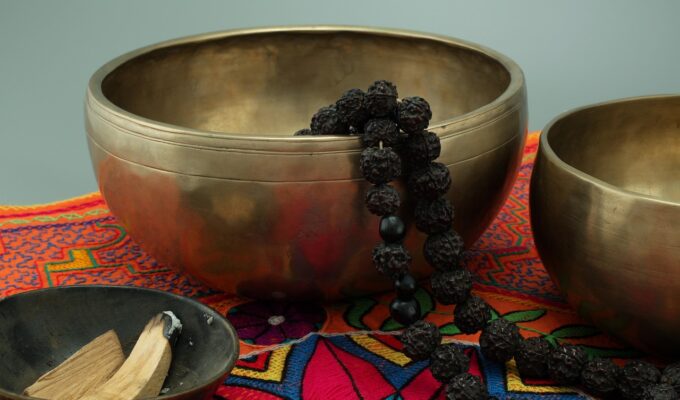Palo santo encendido con humo, acompañado de resinas y frasco de aceite esencial sobre tabla de madera.