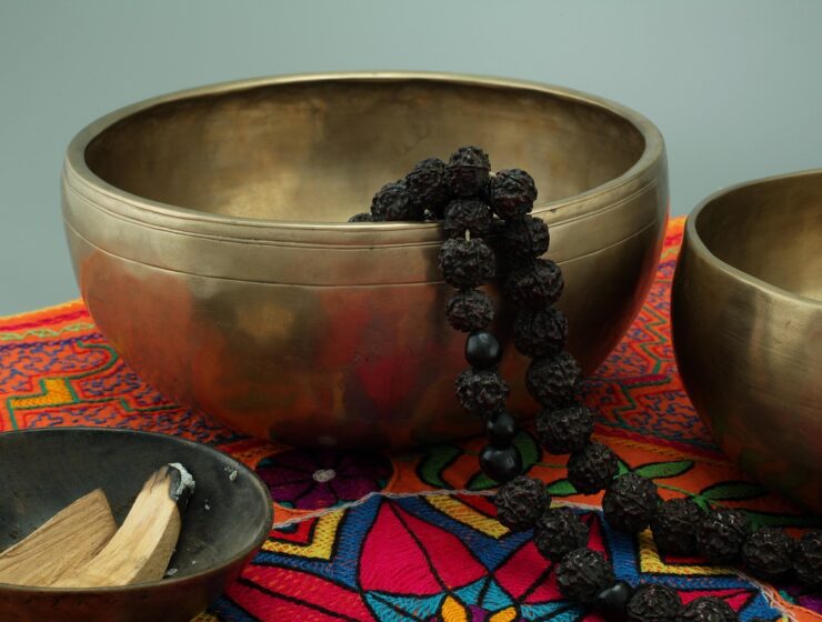 Palo santo encendido con humo, acompañado de resinas y frasco de aceite esencial sobre tabla de madera.