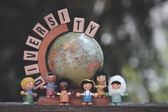 Figuras de niños de diversas etnias frente a un globo terráqueo para ilustrar el concepto de diversidad e inclusión promovido por el movimiento woke en EE.UU.