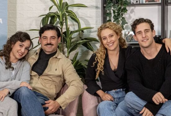 Los actores Ana Garcés (Jana) y Enrique Fortún (López Ruiz) de La Promesa, quienes son pareja en la vida real, sonriendo en una foto junto a otros compañeros de reparto.