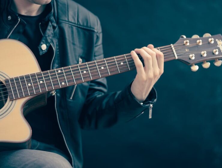 Las guitarras más caras del mundo en 2025 9 Un hombre practica guitarra mientras sigue una clase en línea desde una tablet, usando una app pensada para principiantes.