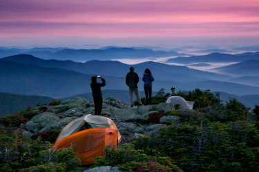 Hikers view the sunrise from a mountaintop.