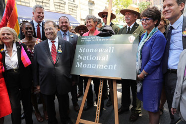 People pose next to a National Park Service sign for the Stonewall National Monument.