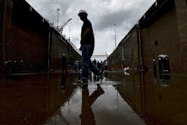 A group of workers in hard hats walk through the shallow water of one of the Panama Canal's locks.